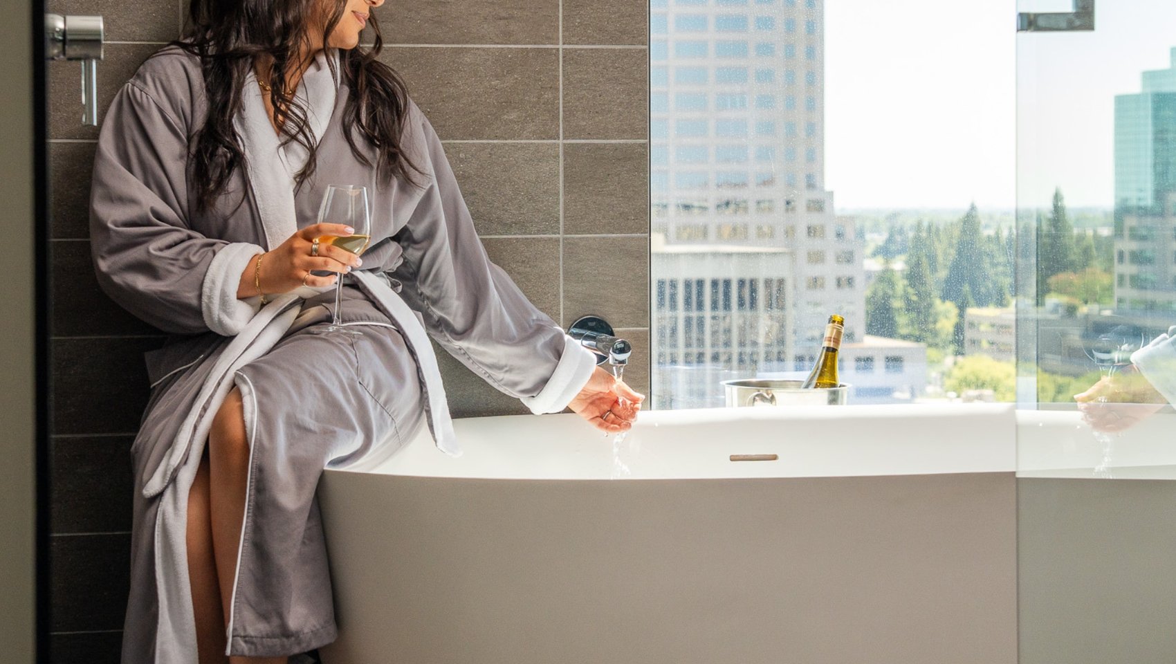 Guest relaxing by bathtub with city views at Kimpton Sawyer Hotel