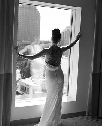 black and white photo of bride in wedding dress looking out the window